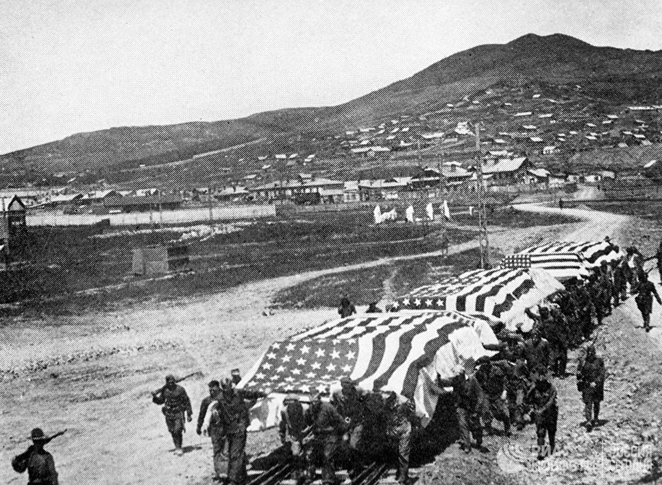 Обоз везёт платформы с мёртвыми американскими оккупантами, которые погибли во время боев на Дальнем Востоке, для дальнейшей транспортировки в США. 1920 год